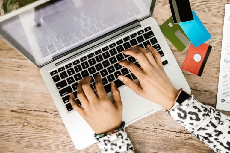 Persona usando laptop con tarjetas de crédito sobre la mesa evaluando sus puntos y millas