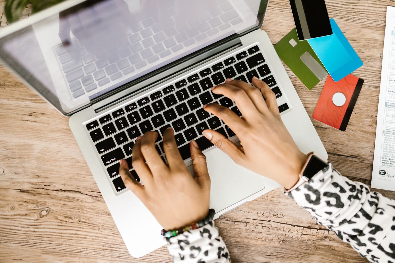 Persona usando laptop con tarjetas de crédito sobre la mesa evaluando sus puntos y millas