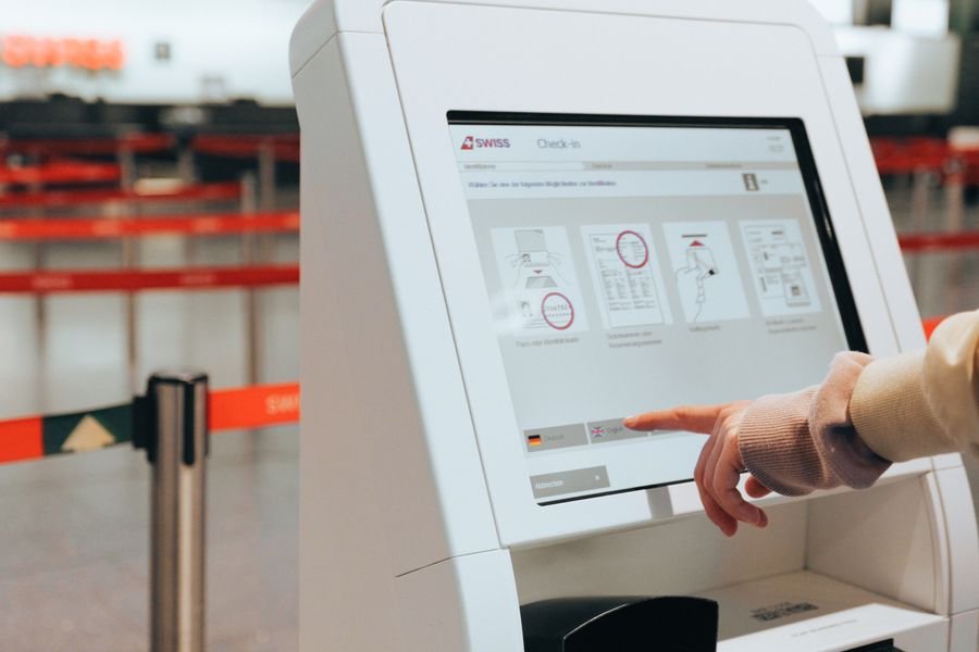 Viajero haciendo check-in en un kiosco de aerolínea, beneficio típico de una tarjeta afiliada a aerolínea