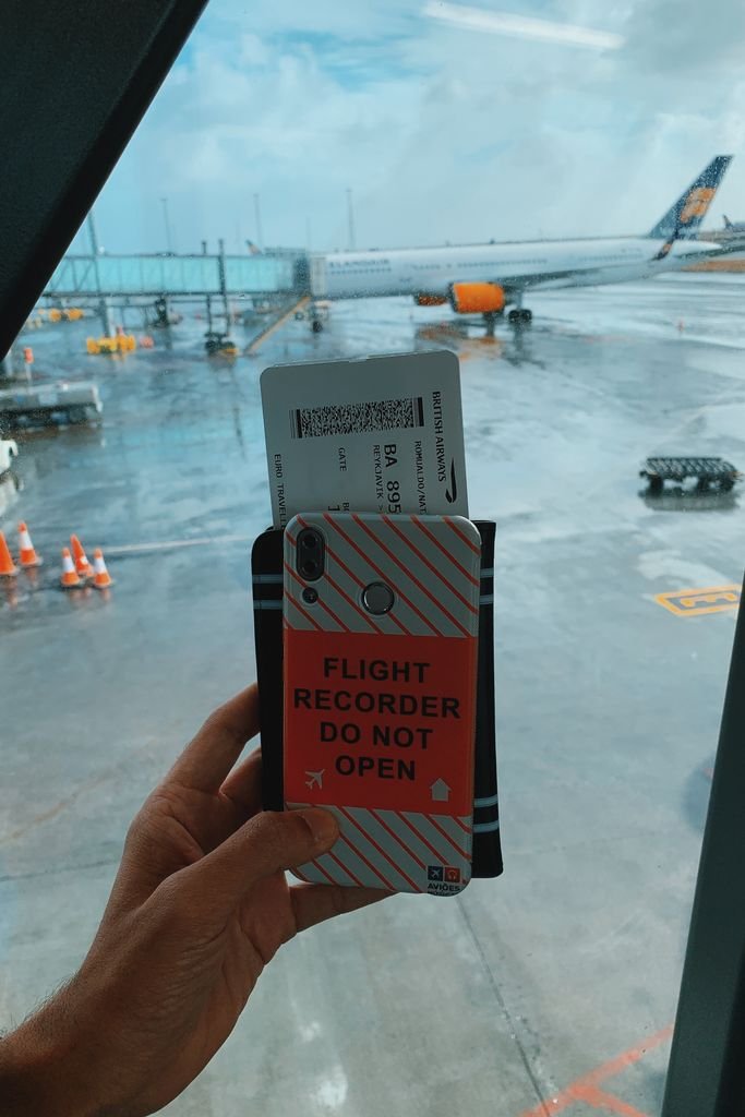 Viajero con celular y pase de abordar en el aeropuerto buscando vuelos baratos con inteligencia artificial