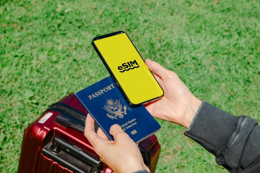 Celular con eSIM activada junto a pasaporte y maleta antes de un viaje internacional